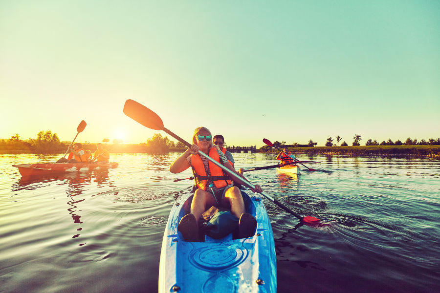 Couples kayaking on lake at sunset 