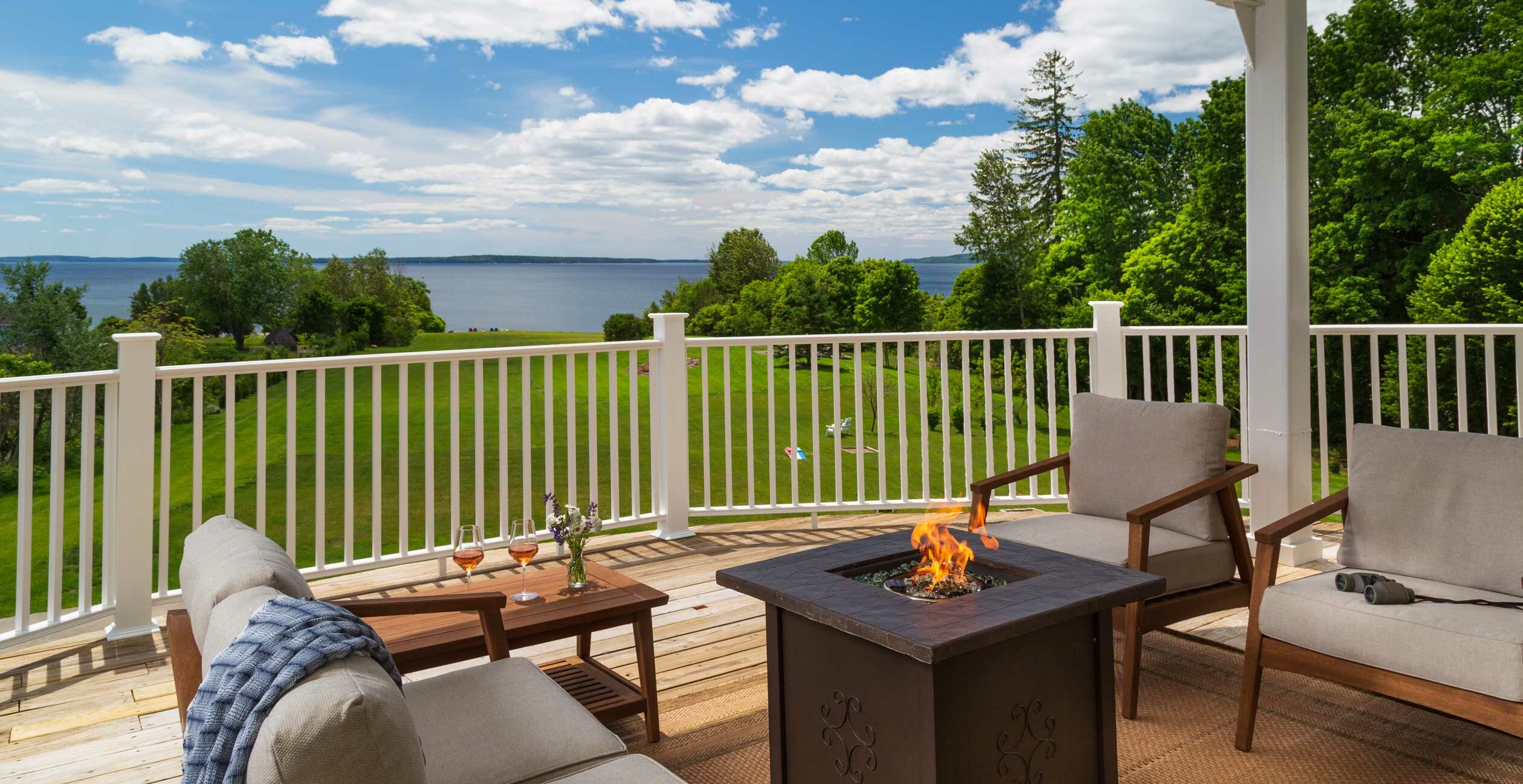Fire pit on private deck overlooking an expansive lawn and the Maine coast