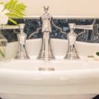 Pedestal sink in blue tiled bathroom and white flowers