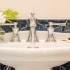 Pedestal sink in blue tiled bathroom and white flowers