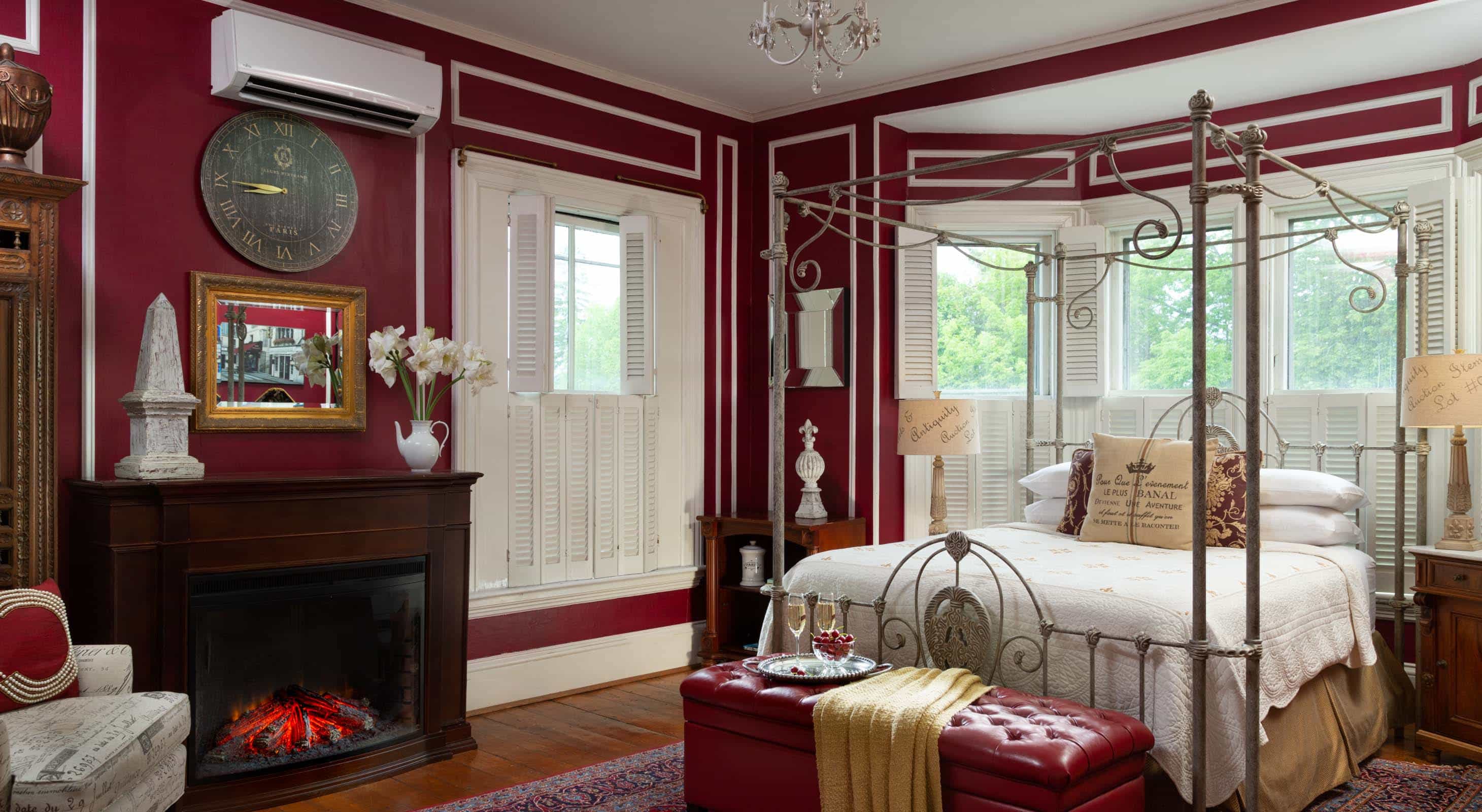 Four-poster queen bed in a room with burgundy painted walls and a fireplace
