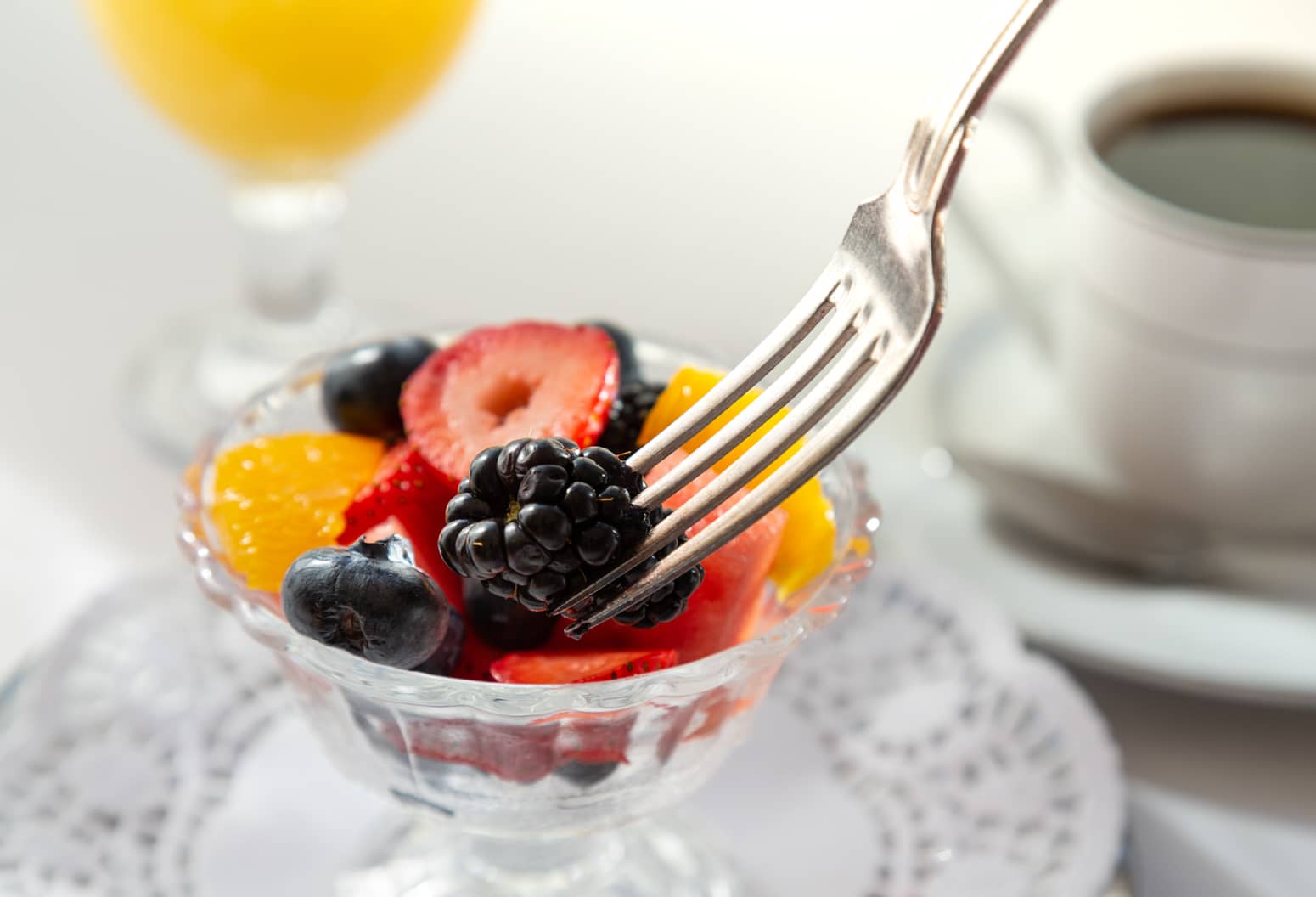 Fresh fruit in a glass dish served with coffee and orange juice