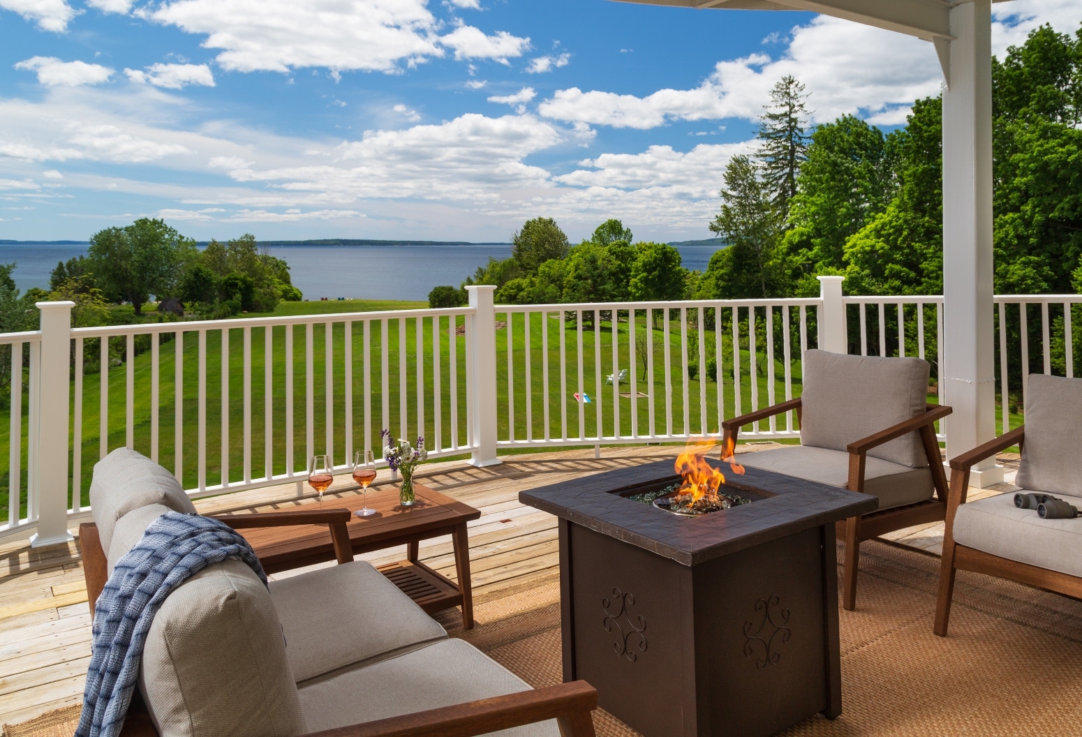 covered deck with firepit and chairs facing water views