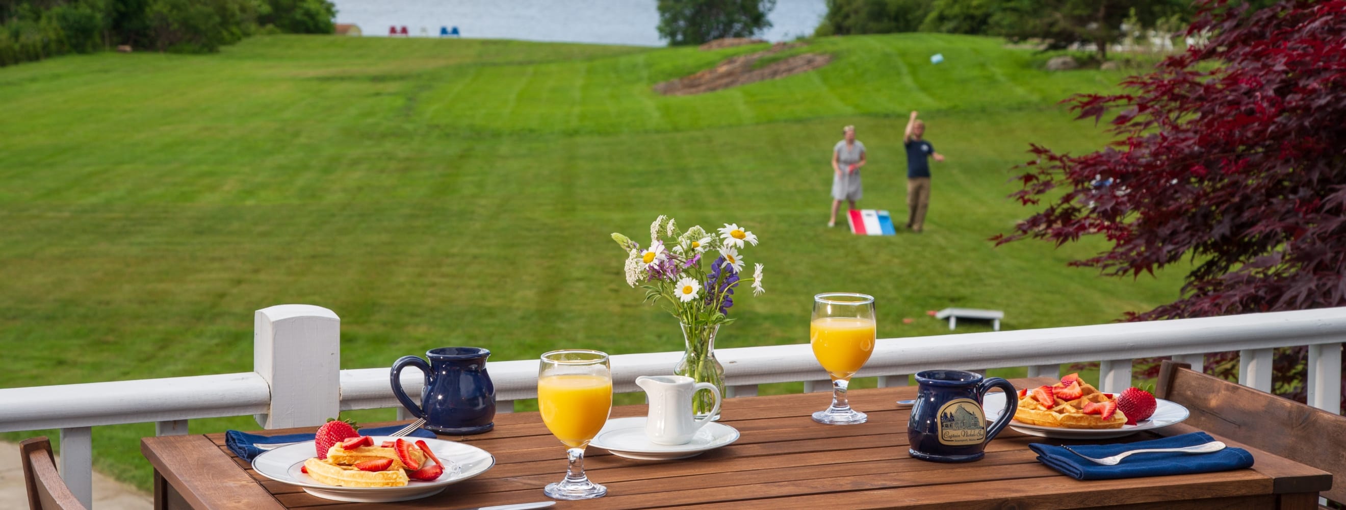 breakfast on tables with couple playing cornhole in the background